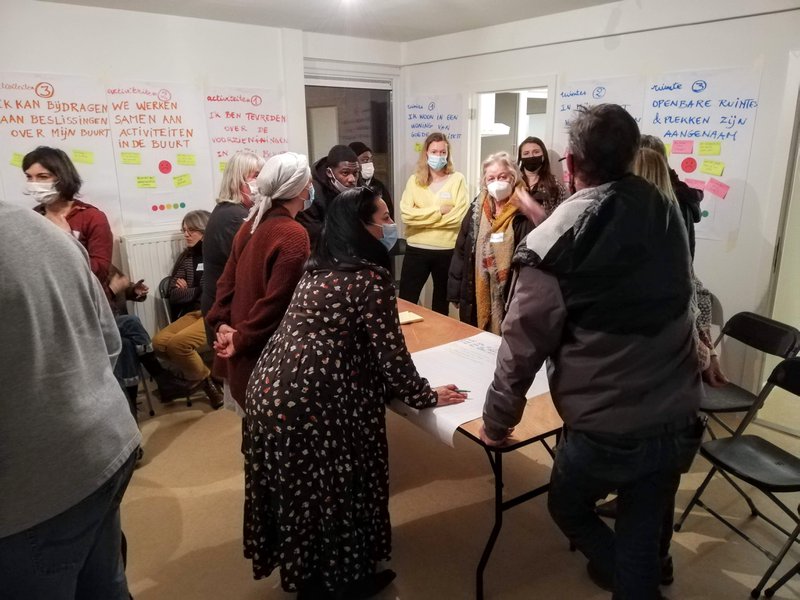 Buurtbewoners bespreken ideeën rond een tafel tijdens een workshop in Oppem